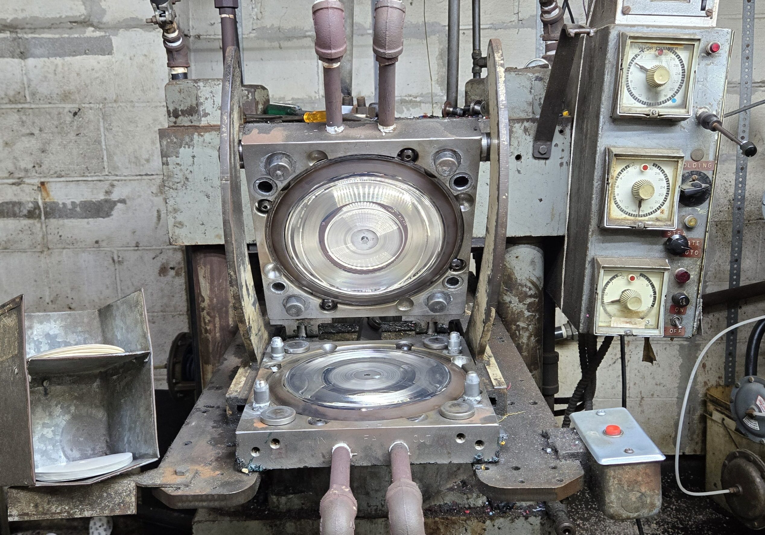 Industrial machine with circular mold and multiple handles in a workshop.